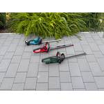 Drei Akku-Heckenscheren liegen auf einem gepflasterten Boden