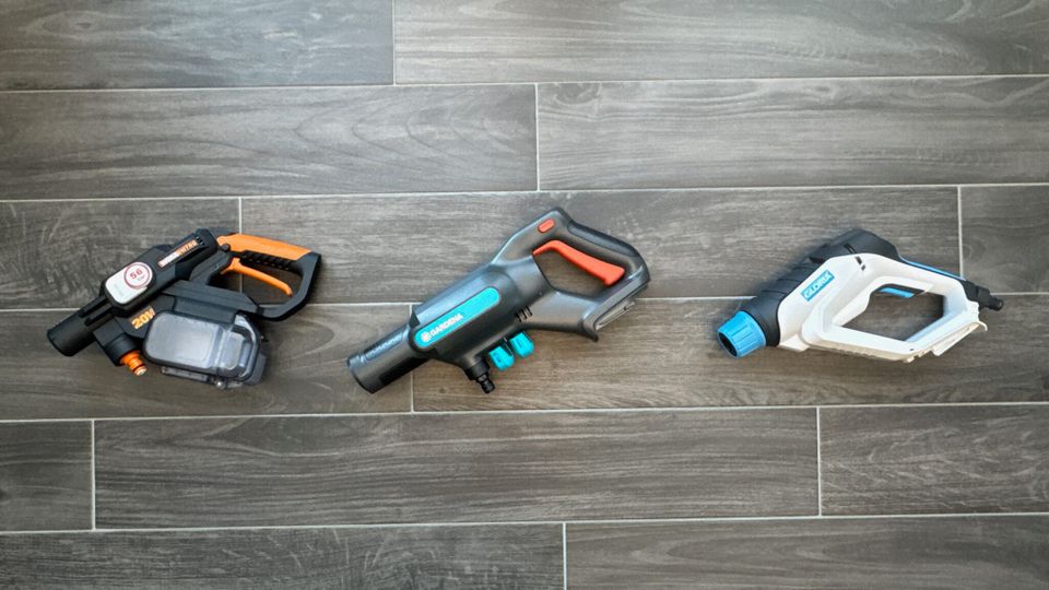 Drei Hochdruckreiniger nebeneinander auf dem Boden.