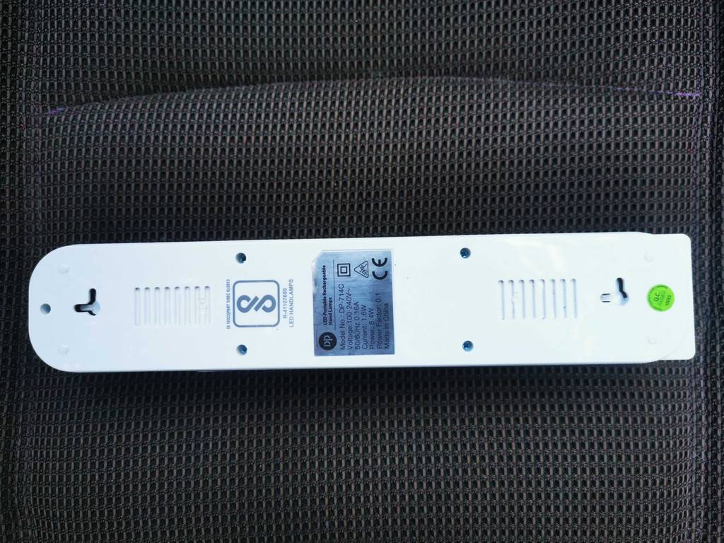 Eine Akku-Lampe liegt zum testen mit der Rückseite nach oben auf einem dunklen Polster.