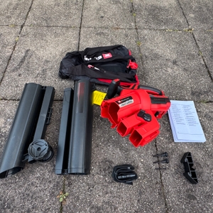 Der getestete Einhell-Akku-Laubsauger liegt mit dem Zubehör auf dem Boden.