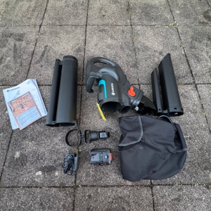 Der getestete Gardena-Akku-Laubsauger liegt mit dem Zubehör auf dem Boden.