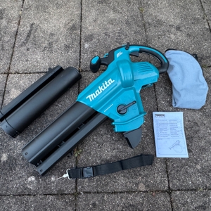 Der getestete Makita-Akku-Laubsauger liegt mit dem Zubehör auf dem Boden.