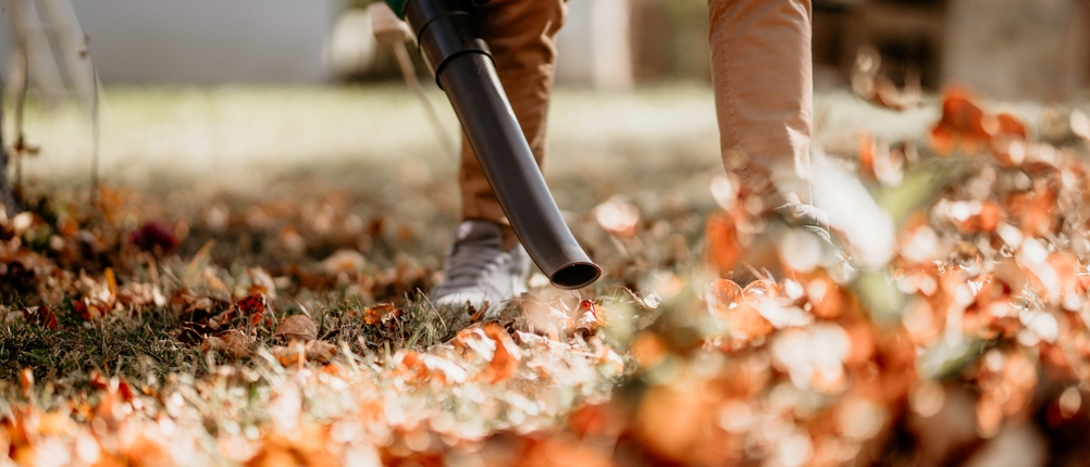Mann beim Laubsauger-Test im herbstlichen Garten.