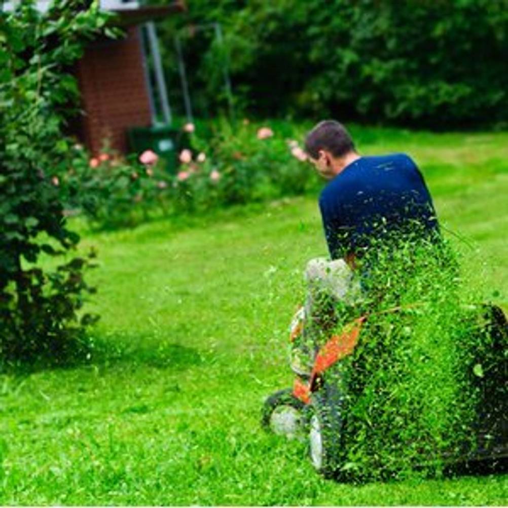 Mann, der auf einem Rasentraktor seinen Rasen mäht