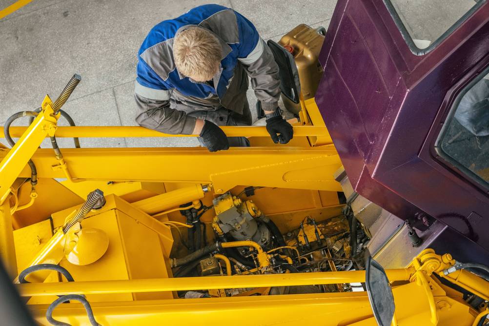 Akku-Ratsche im Test: Aufnahme von oben. Ein Mann schaut in den Motor einer Landmaschine.