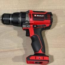 Der Einhell Professional Akku-Schlagbohrschrauber liegt unbenutzt auf einem hellen Holzboden. Das Gerät ist vollständig abgebildet und gut ausgeleuchtet.