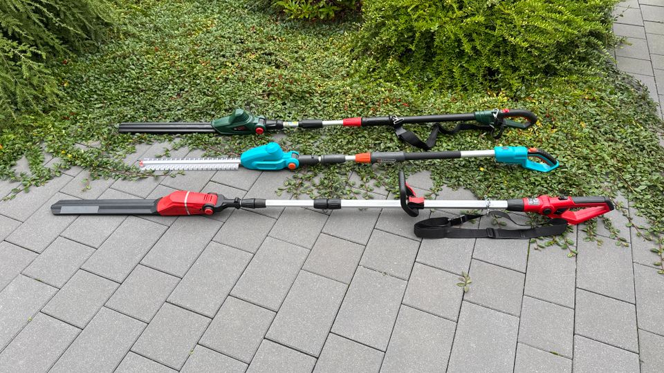 Drei Akku-Teleskop-Heckenscheren liegen nebeneinander auf einem Tisch