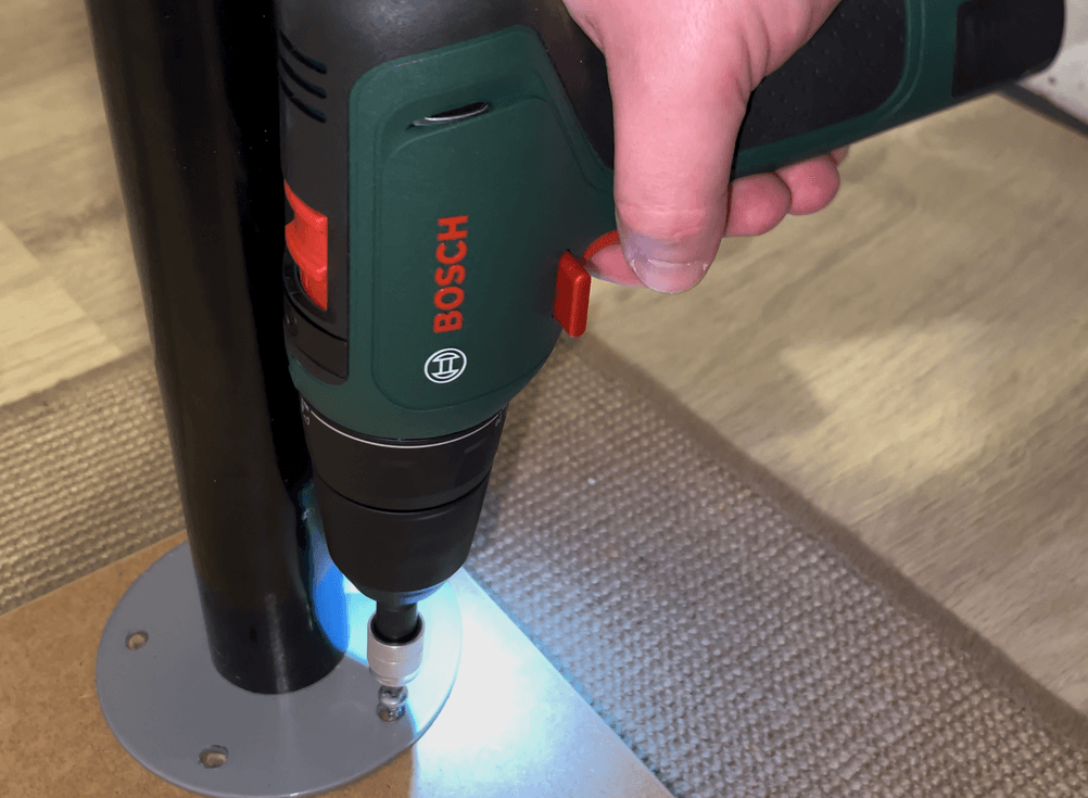 Der Bosch EasyDrill 1200 wird auf einer flachen Unterlage getestet, die LED-Beleuchtung leuchtet den Arbeitsbereich mit blauem Licht aus. Die Einhandbedienung ermöglicht sicheres Führen während des Schraubvorgangs.