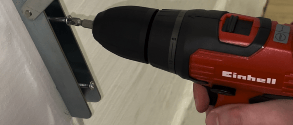 Detailansicht des Bohrfutters vom Einhell TH-CD 12-2 Li mit eingesetztem Bit. Der Schrauber befindet sich nahe an einer Metallkonstruktion.