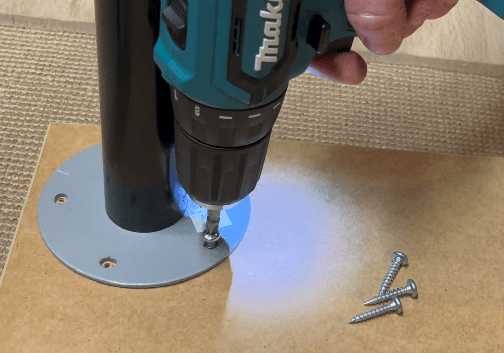 Makita DF333DSAE Akkuschrauber dreht eine Schraube in eine Metallplatte an einem Rohr. Das LED-Licht beleuchtet den Arbeitsbereich von oben.