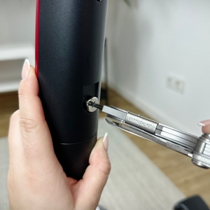 Ein Multitool zieht eine Schraube an einem schwarzen Saugrohr des AEG Ergorapido CX7-2-45AN fest. Eine Hand hält das Rohr stabil.