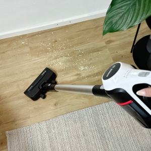 Eine Person saugt Holzspäne auf einem Laminatboden mit dem Bosch Unlimited Serie 6 BCS611AM. Die schwarze Düse ist im Einsatz.