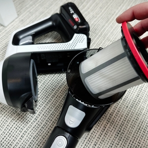 Ein herausgenommener Filter des Bosch Unlimited Serie 6 BCS611AM liegt auf einem Teppichboden. Eine Hand hält den Filtereinsatz.