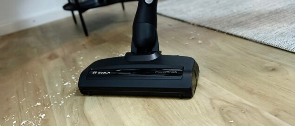 Nahaufnahme der PowerBrush-Düse des Bosch Unlimited Serie 6 BCS611AM auf einem Laminatboden mit Holzspänen.