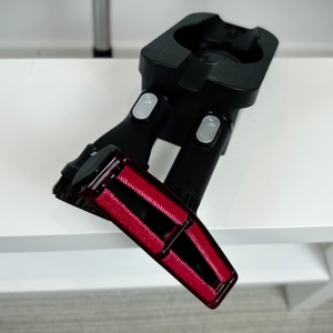 Ein rot-schwarz kombinierter Staubsaugeraufsatz der Bosch Unlimited Serie 6 liegt auf einem weißen Tisch. Zwei weitere Zubehörteile sind sichtbar.