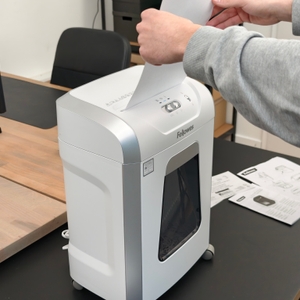 Eine Person führt ein Blatt Papier in einen Aktenvernichter ein.