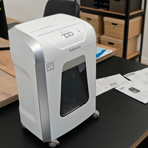 Ein weißer Fellowes-Aktenvernichter auf einem Schreibtisch.
