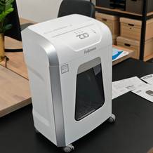 Ein weißer Aktenvernichter von Fellowes auf einem schwarzen Tisch.