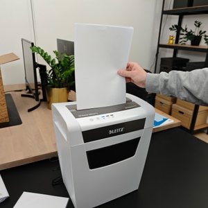 Eine Person befüllt einen Leitz IQ Home Office mit einem Stapel Papier.