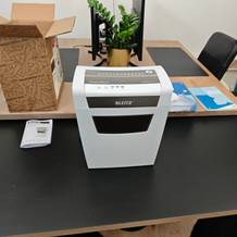 Ein weißer Aktenvernichter von Leitz auf einem schwarzen Tisch.