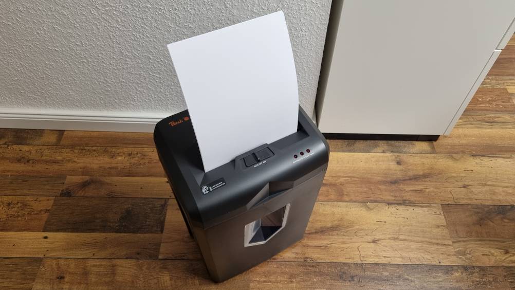 Aktenvernichter mit Papier oben drin steht auf dem Boden