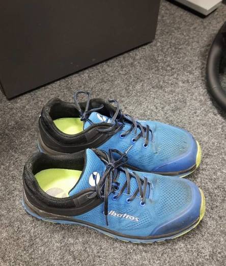 Blaue Albatros Sicherheitsschuhe im Test befinden sich auf einem grau melierten Teppichboden.