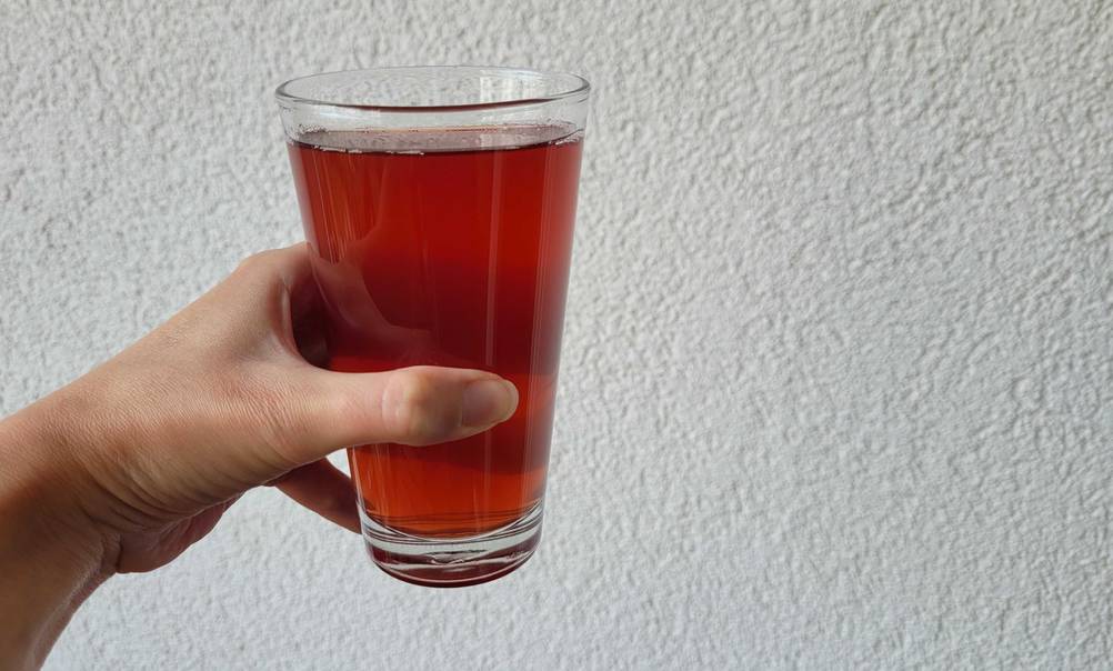 Ein volles Glas Cranberrysaft in der Hand