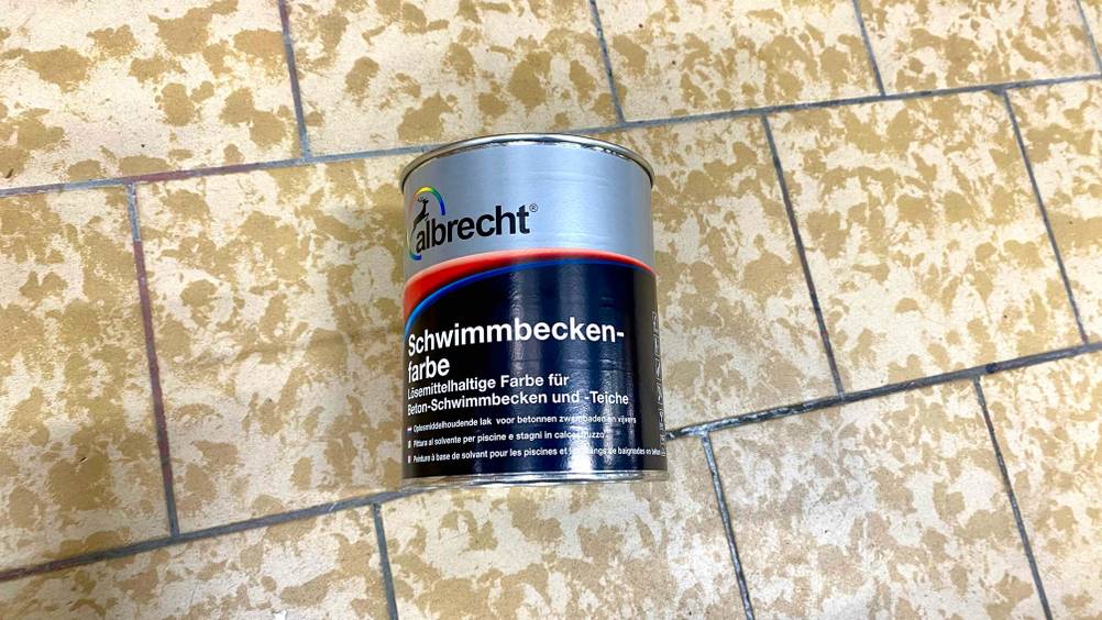 Behälter mit getesteter Schwimmbadfarbe liegt auf dem Boden.