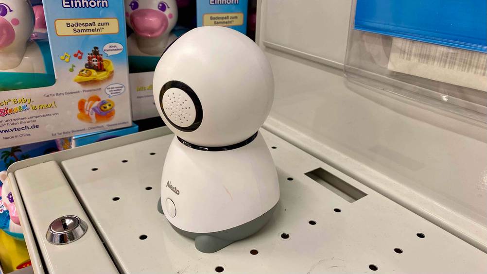 Babyphone mit Kamera-App getestet: Ein Gerät von der Seite, steht auf einem weißen Metallkasten neben anderen Produkten.