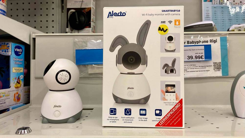 Eine getestetes Babyphone mit Kamera-App steht neben seiner Originalverpackung in einem Verkaufsregal inklusive Preisangabe im Hintergrund.