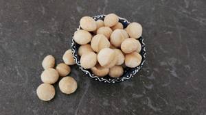 Macadamia-Nüsse-Test: mehrere Nüsse befinden sich in einer Schale für Snacks auf einem schwarzen Untergrund.