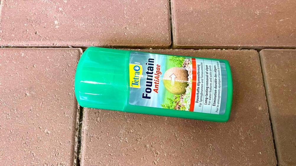 Eine Flasche des getesteten Algenentferners horizontal auf einem Steinboden liegend.