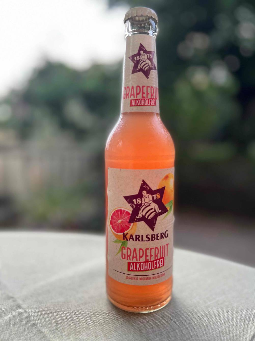 Eine Flasche getestetes alkoholfreies Bier auf einer grauen Tischdecke.
