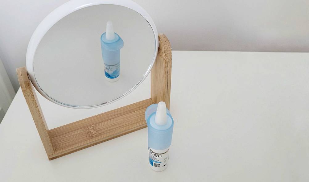 Allergie-Augentropfen getestet: Vor einem Spiegel steht ein Fläschchen Augentropfen.