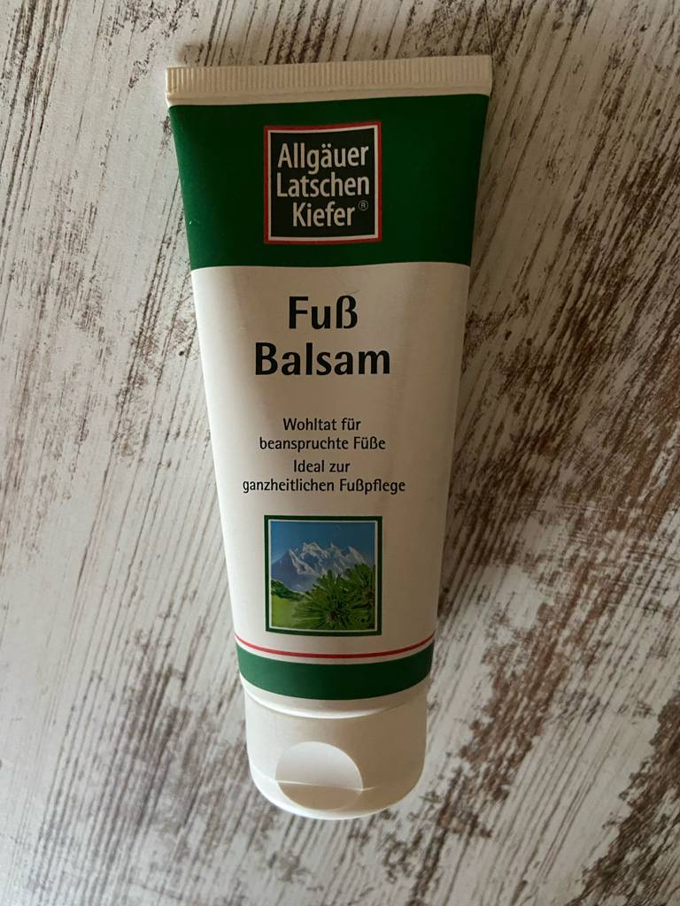 Nahansicht einer Tube Hornhaut-Creme im Test, die auf einer Holzfläche liegt.