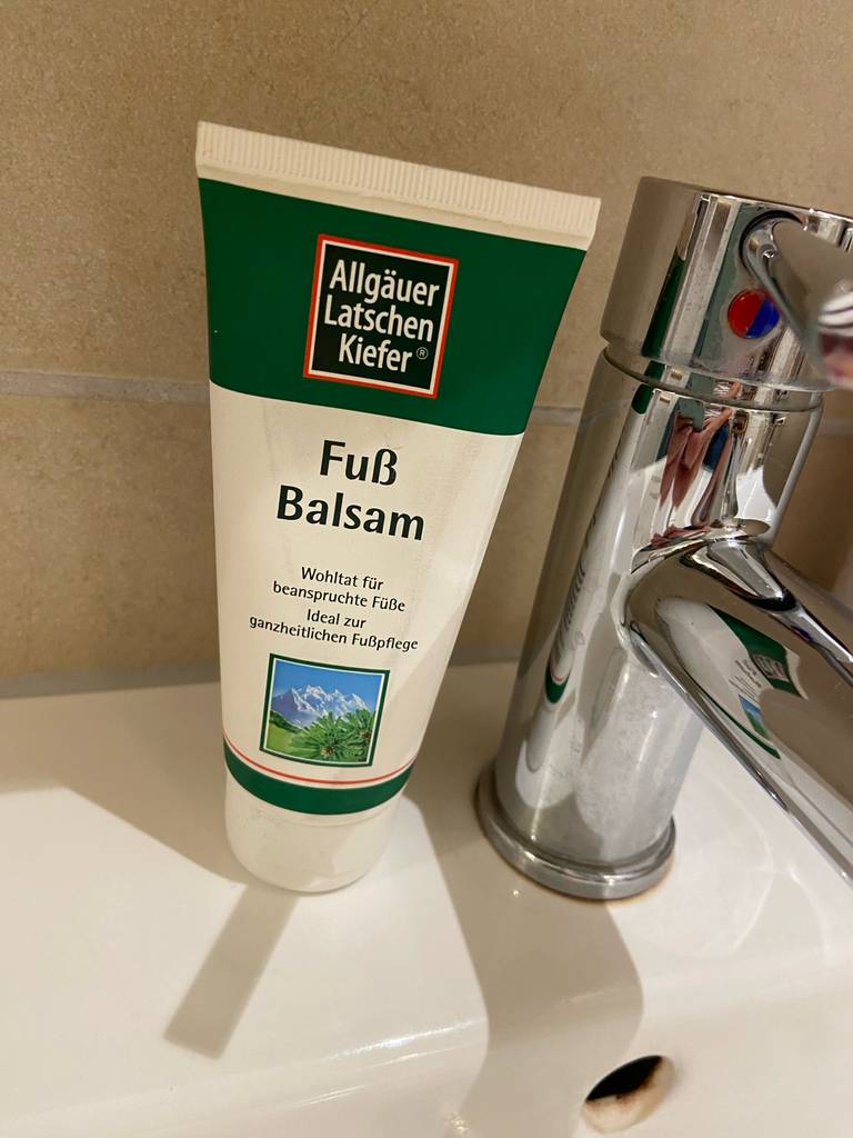 Eine Tube Hornhaut-Creme steht zum testen auf einem Waschbecken neben dem Wasserhahn.