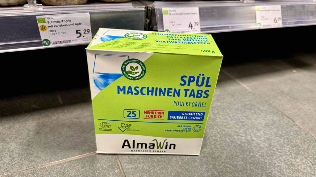Getestete Öko-Spülmaschinentabs in der grünen Verpackung stehen vor einem Verkaufsregal.