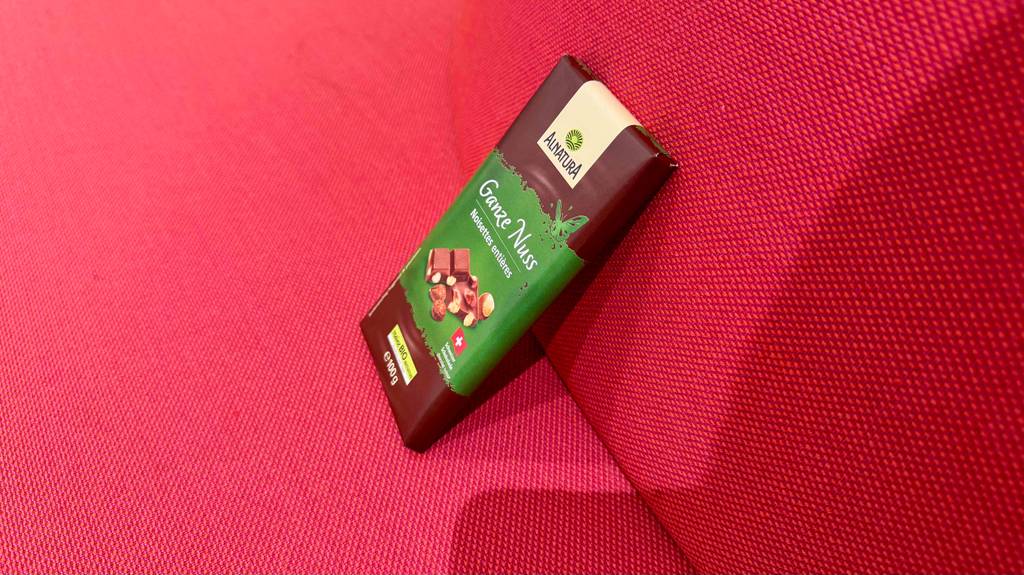 Eine Tafel Bio-Schokolade steht zum Testen auf einer roten Couch, von der Seite betrachtet.