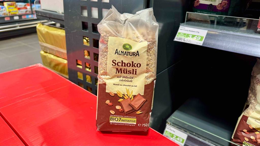 Eine Packung getestetes Schoko-Müsli steht auf einem roten Karton vor einem Verkaufsregal.