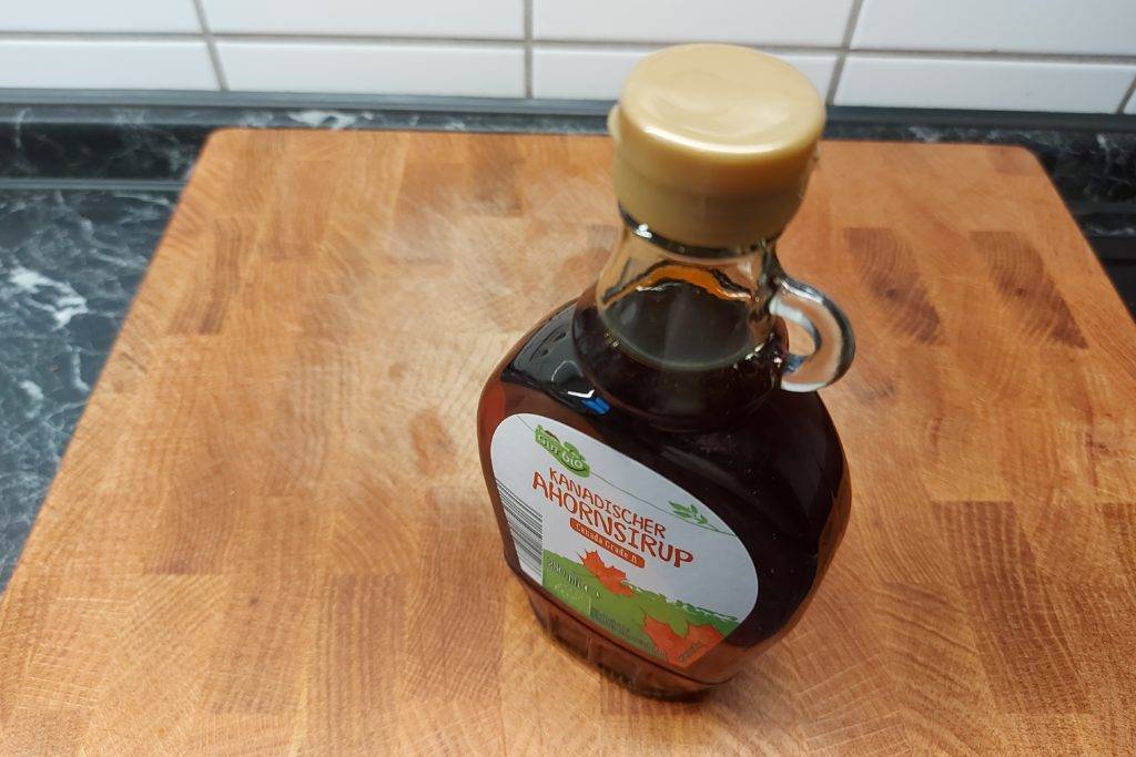 Im Test: Eine Flasche Gut Bio Ahornsirup steht auf einer Holz-Arbeitsfläche.