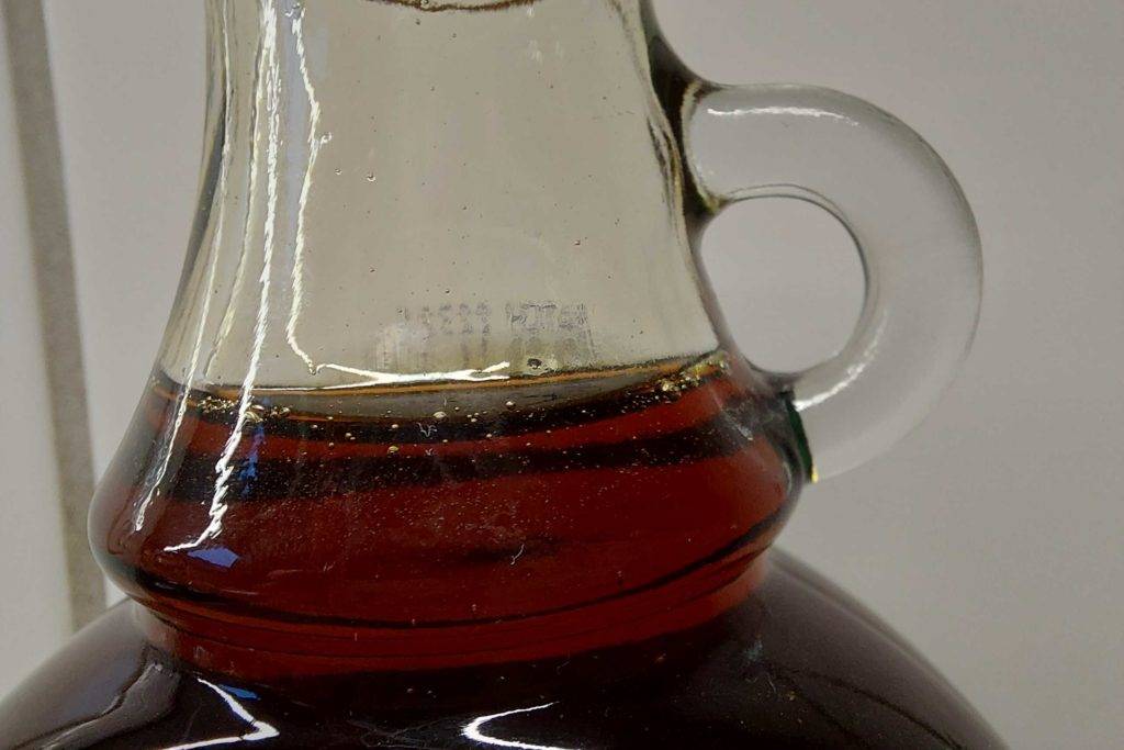 Glashenkel einer Flasche getesteter Ahornsirup.