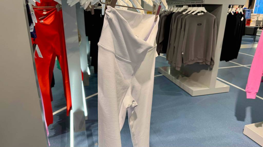 Die weiße, getestete Yoga-Pants mit Hüftbund ohne Gummi hängt auf einem Bügel im Geschäft.