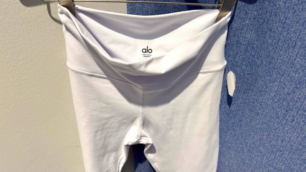 Im Test: Die Yoga-Pants in Weiß haben einen Hüftbund ohne Gummi und hängen auf einem Bügel vor einem Jeansstoff.
