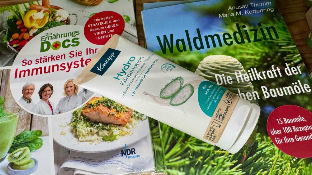 Auf mehreren Zeitschriften liegt eine Tube der Aloe-vera-Bodylotion im Test.