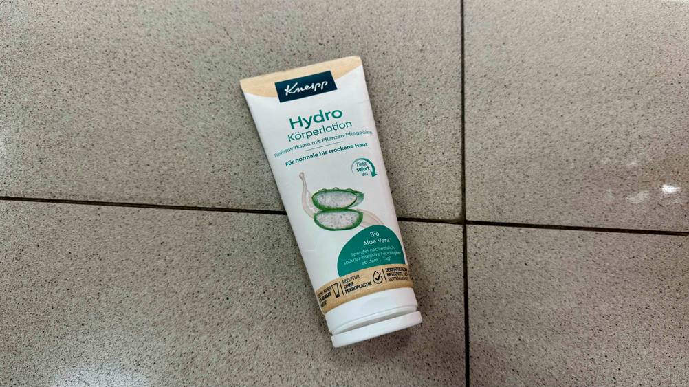 Eine Tube der getesteten Aloe-vera-Bodylotion liegt auf einem Fließenboden.