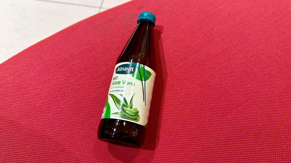 Auf einem roten Polster liegt eine Flasche des getesteten Aloe-vera-Saft (bio).