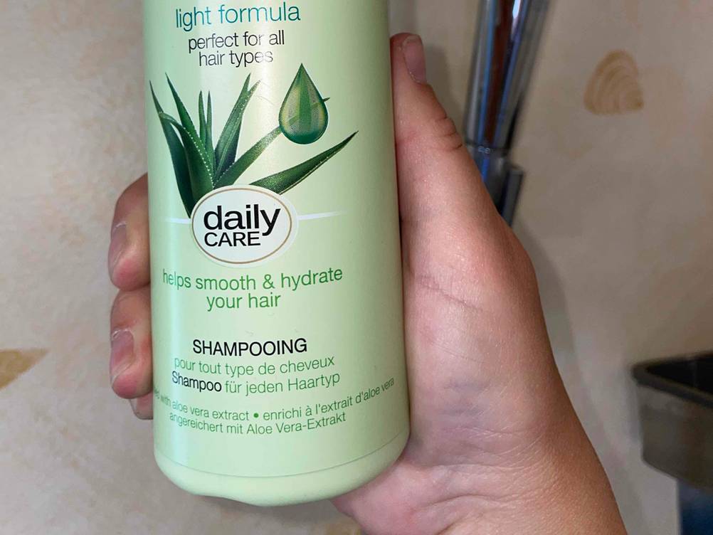 Nahaufnahme der Informationen auf einer Flasche des getesteten Aloe-vera-Shampoos von einer Hand gehalten.