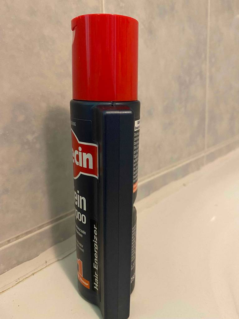 Alpecin-Shampoo getestet: Eine Flasche von der Seite vor einer Fließenwand.