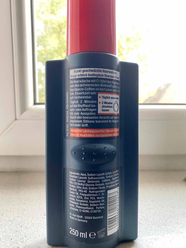 Rückseite einer Flasche des getesteten Alpecin-Shampoos vor einem Fenster.