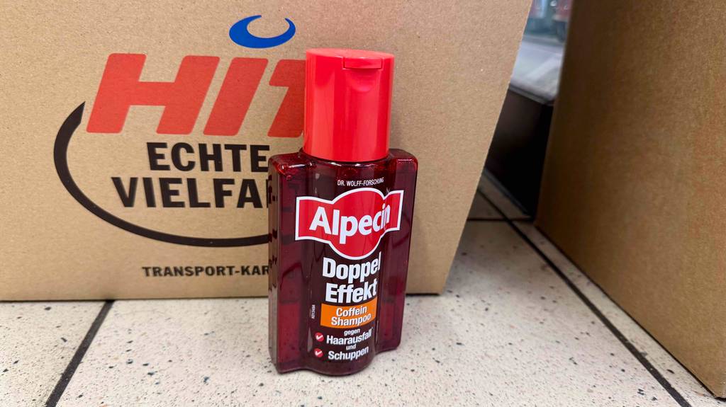 Männer-Shampoo gegen Haarausfall-Test: Nahblick auf den Spenderdeckel einer Flasche, die vor einem Karton steht.